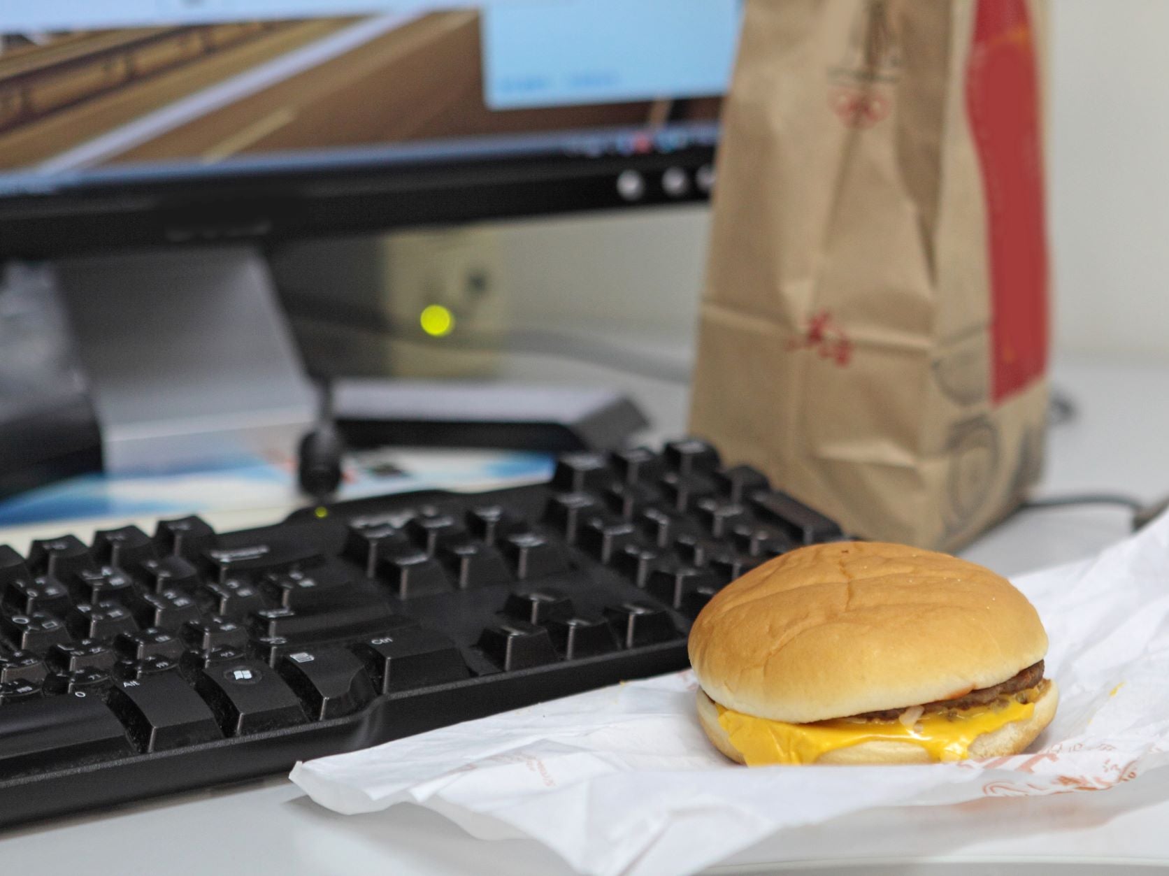 Poor Diet might lead to sleeping too much, fast food lunch in front of computer at desk