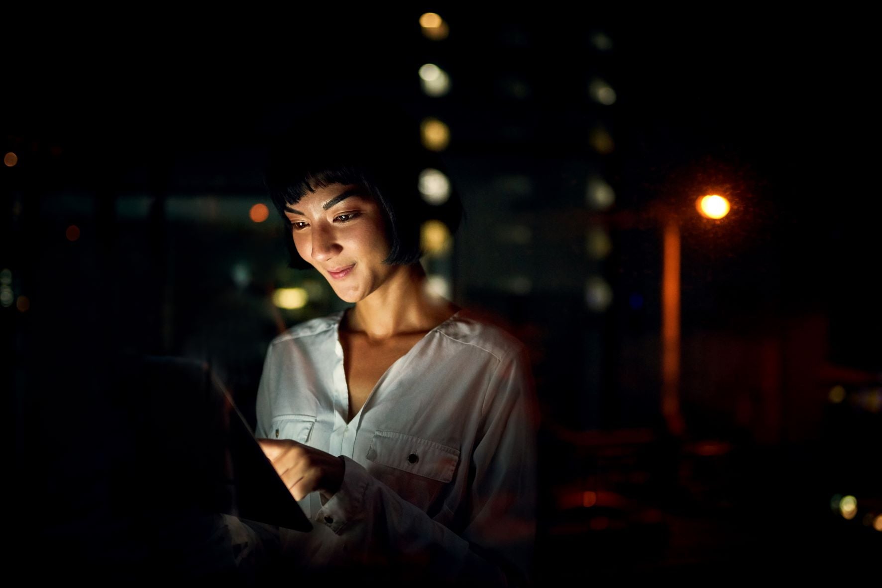 Young woman looking at screen emitting blue light to stay up all night