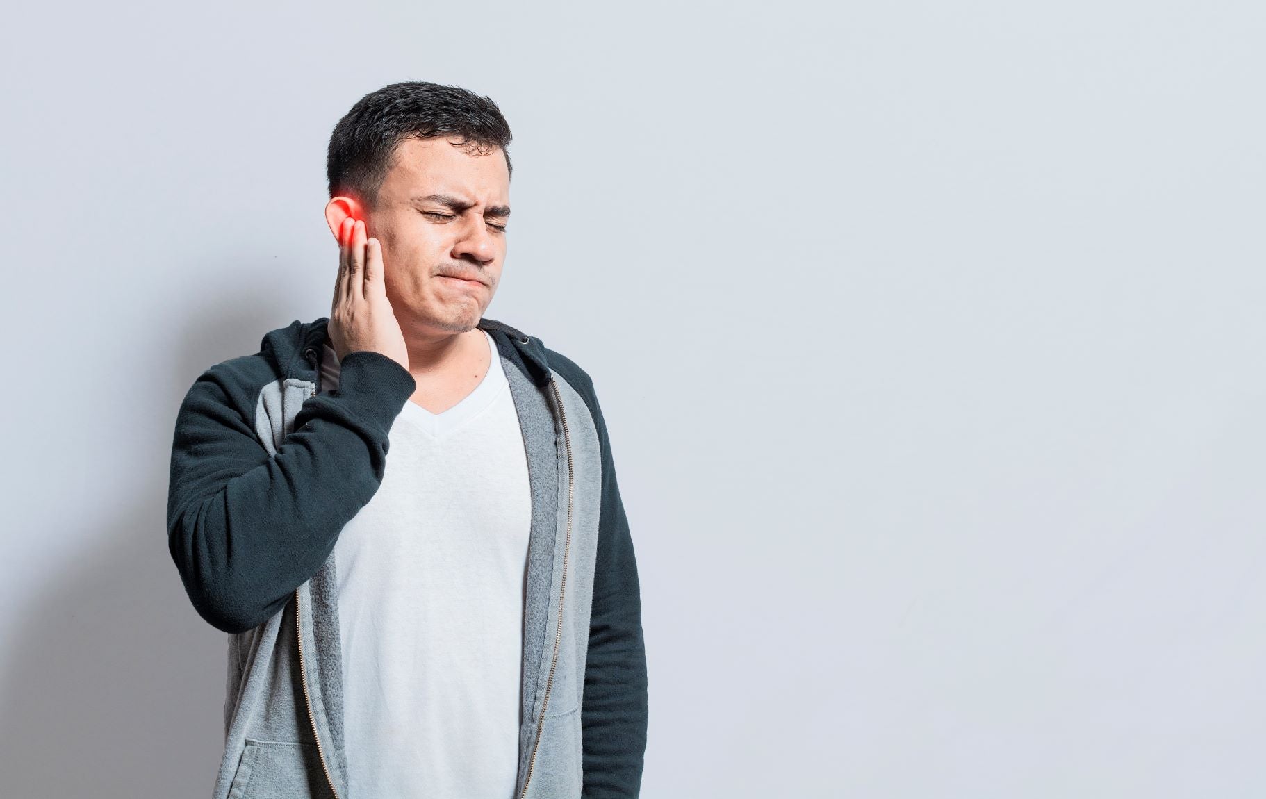 Man suffering from CNH, holding his ear in pain