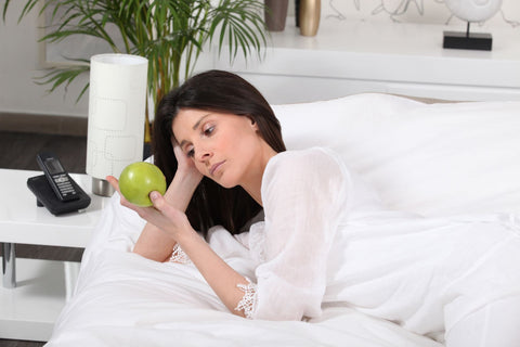 Apples and sleep, woman on bed before sleep staring at an apple