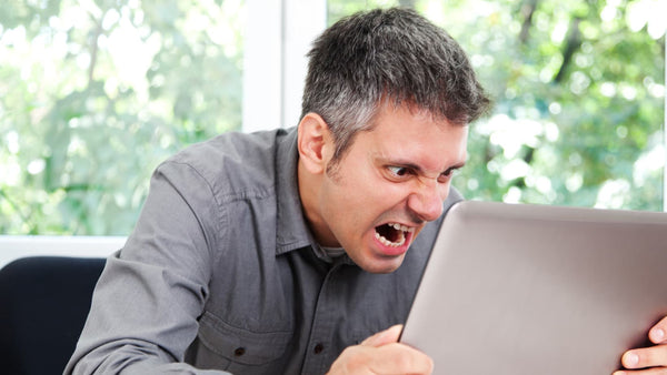 man screaming at laptop, angry man at desk because he's tired, what happens when you don't sleep from snoring, decreased productivity from snoring man at desk angry
