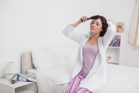 Give your hair a good brush before going to bed, woman sitting on bed brushing her hair