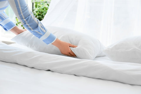 Fluffing a pillow by Hand, a person fluffing pillows on bed by hand