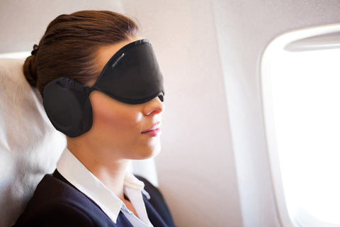 business woman on air plane using Hibermate sleep mask with ear muffs