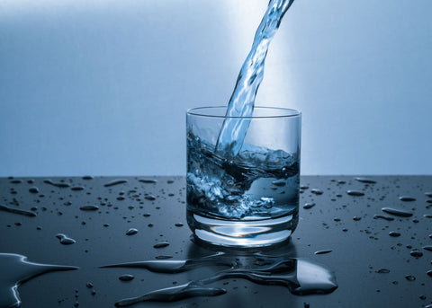 Stay hydrated to avoid sleepiness after meal, water being poured into glass of water