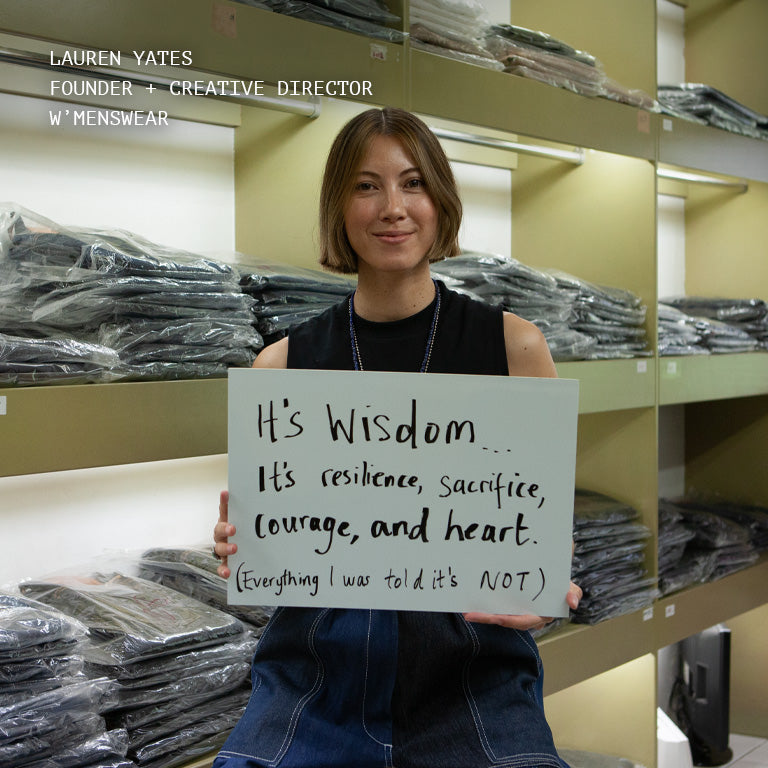 W'MENSWEAR Founder & Creative Director Lauren Yates holding a sign, explaining what femininity means to her.