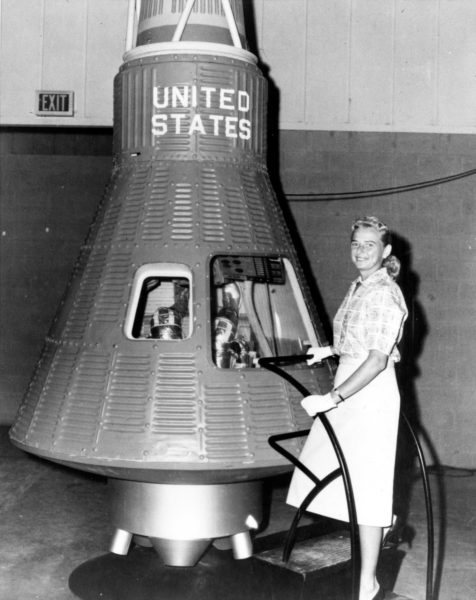 A member of the Mercury 13 -- Jerrie Cobb next to a Mercury spaceship capsule