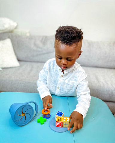 Noah during playtime with puzzle pieces and his blue Eizzy Baby Portable Snack Cup