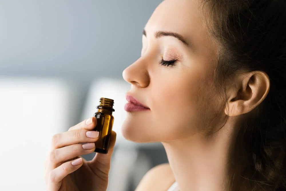 A young lady smelling aromatherapy essential oil