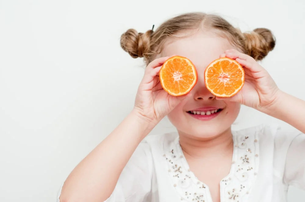 Little girl playing with fresh mandarin
