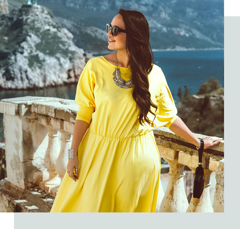 Plus size model in yellow dress in front of rustic mountain background