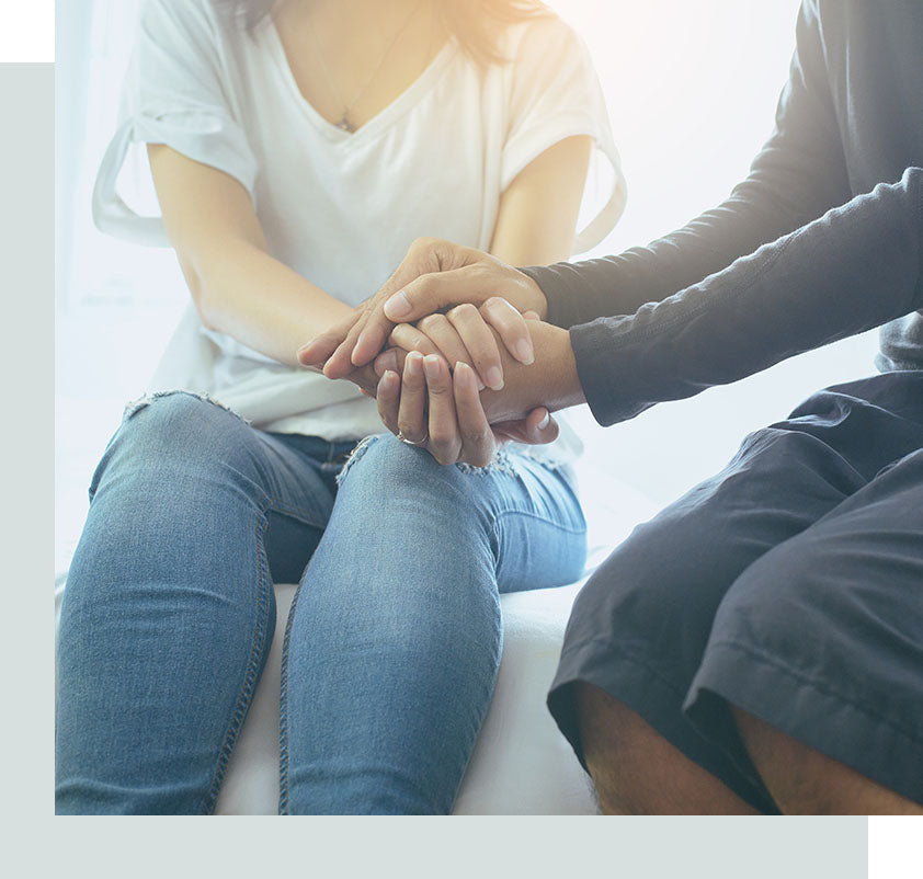 Couple of young adults grasping hands to comfort one another