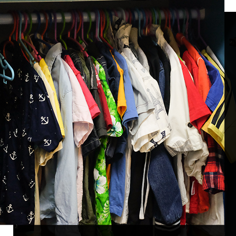 A bunch of shirts hanging in a closet.