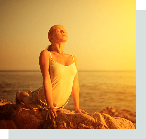 Woman doing yoga on the beach by a sunset.