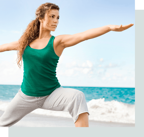 woman doing yoga on the sand by the ocean.