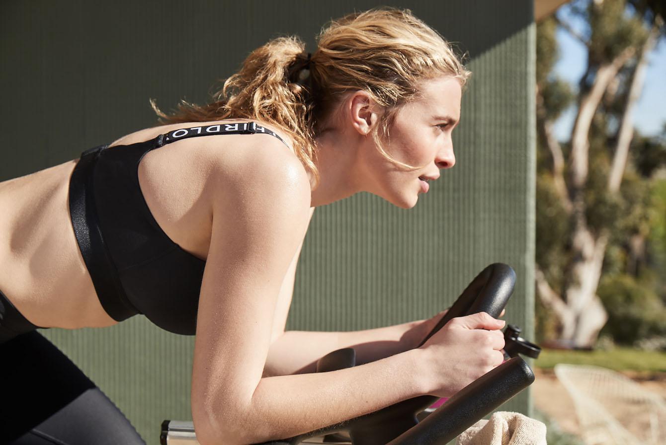 Woman wearing a sports bra and cycling.