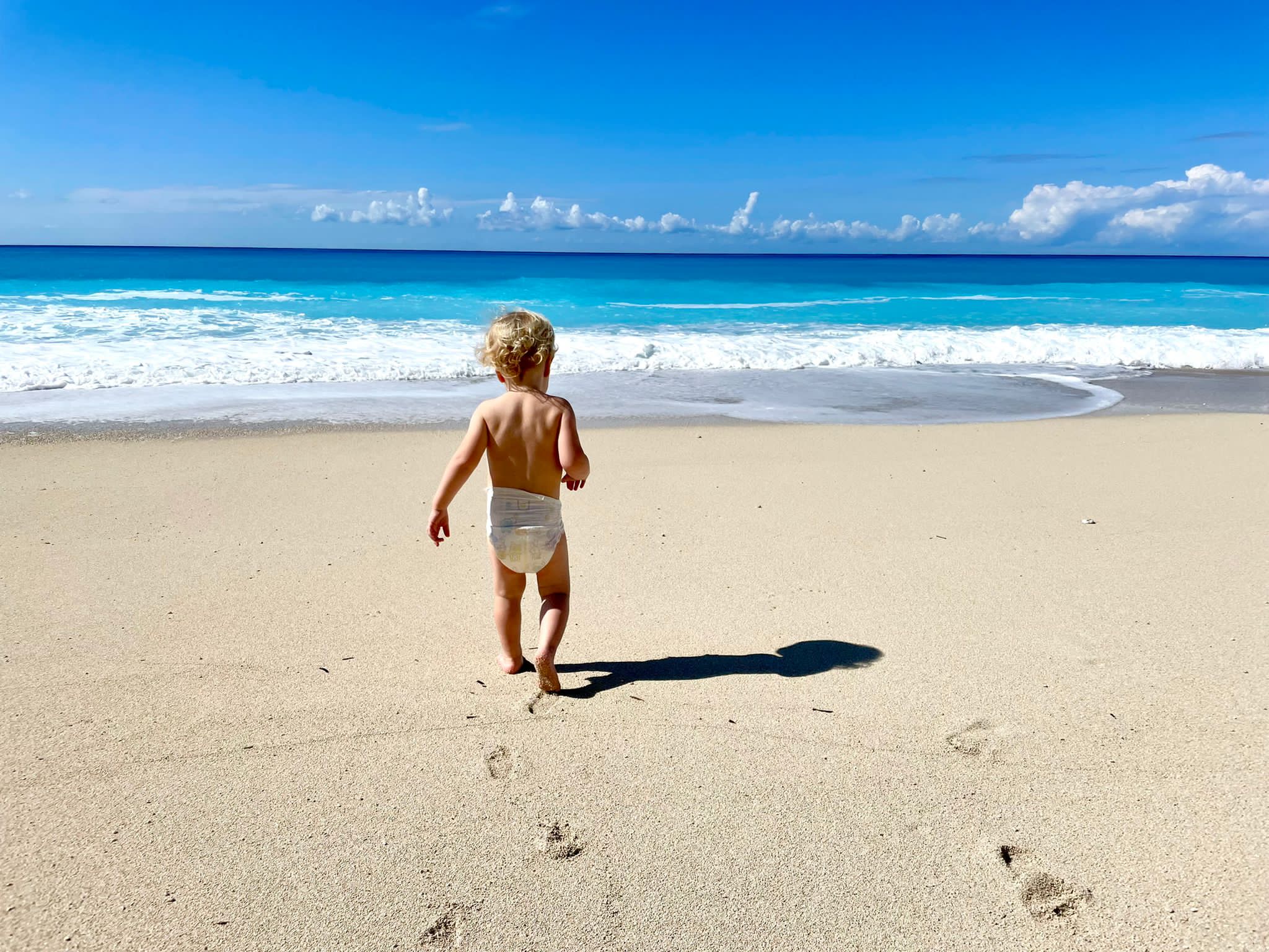 Image of small child walking towards the ocean. Lefkada Greece.