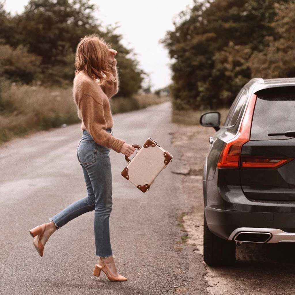 Woman in jeans and a sweater crossing the street with a retro style handbag