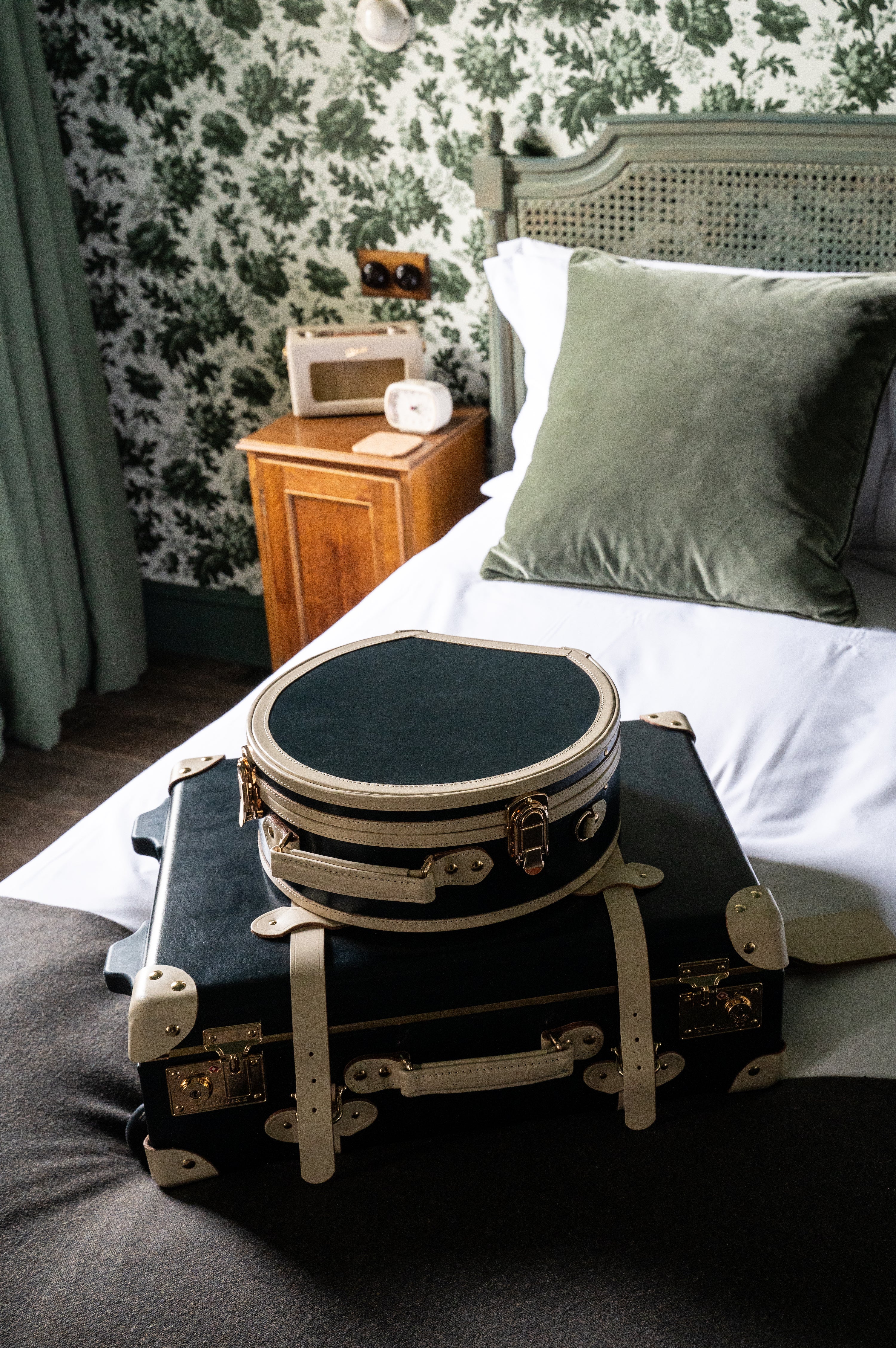 Vintage style trunk luggage and hat box on top of a made bed