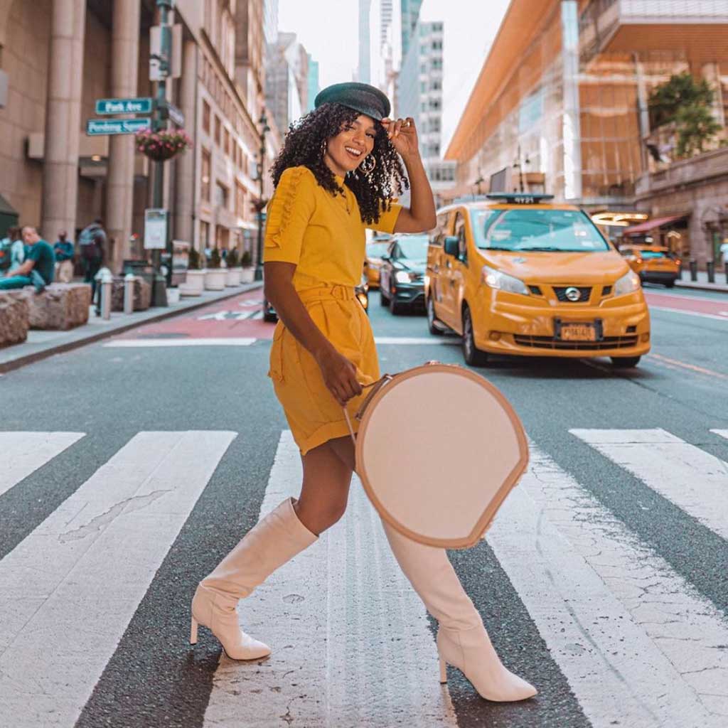 Woman walking at crosswalk with a vintage style hatbox