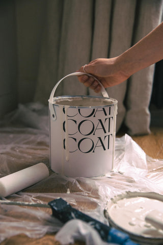 Pot de peinture COAT disposé sur une bâche de protection