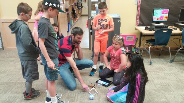 Kids and an instructor doing a classroom activity with a Sphero Bolt robot.