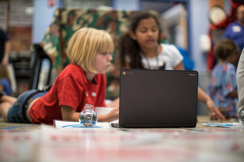 Students sitting on the floor with BOLT robot and laptop.