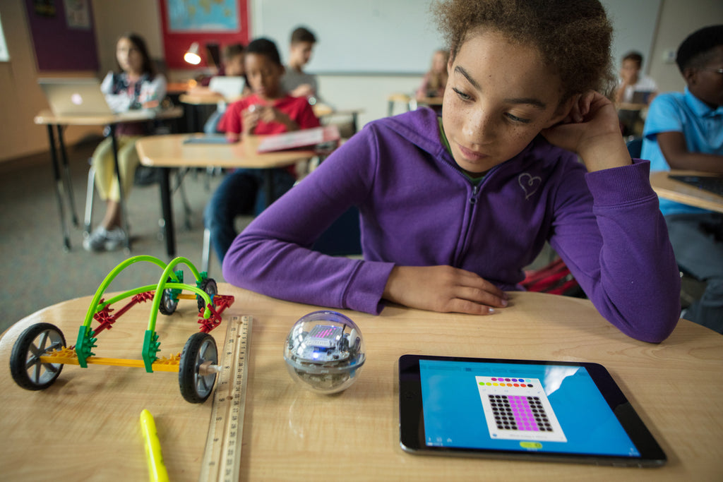 A girl sits at her desk in school programming her Sphero BOLT.