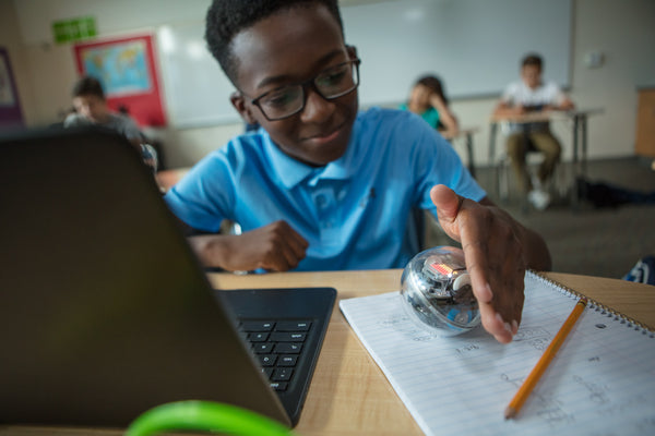 Student sitting at classroom desk with laptop coding BOLT