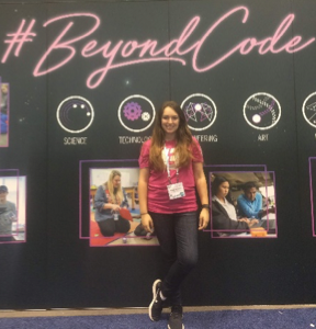 Woman standing in front of Sphero display that says #BeyondCode.