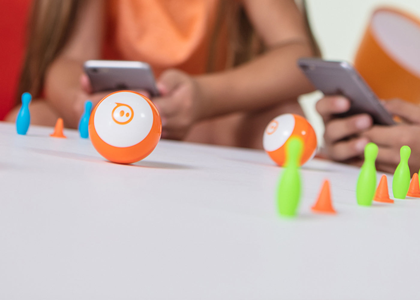 Boules de robot jouet orange roulant à travers des épingles et des cônes.