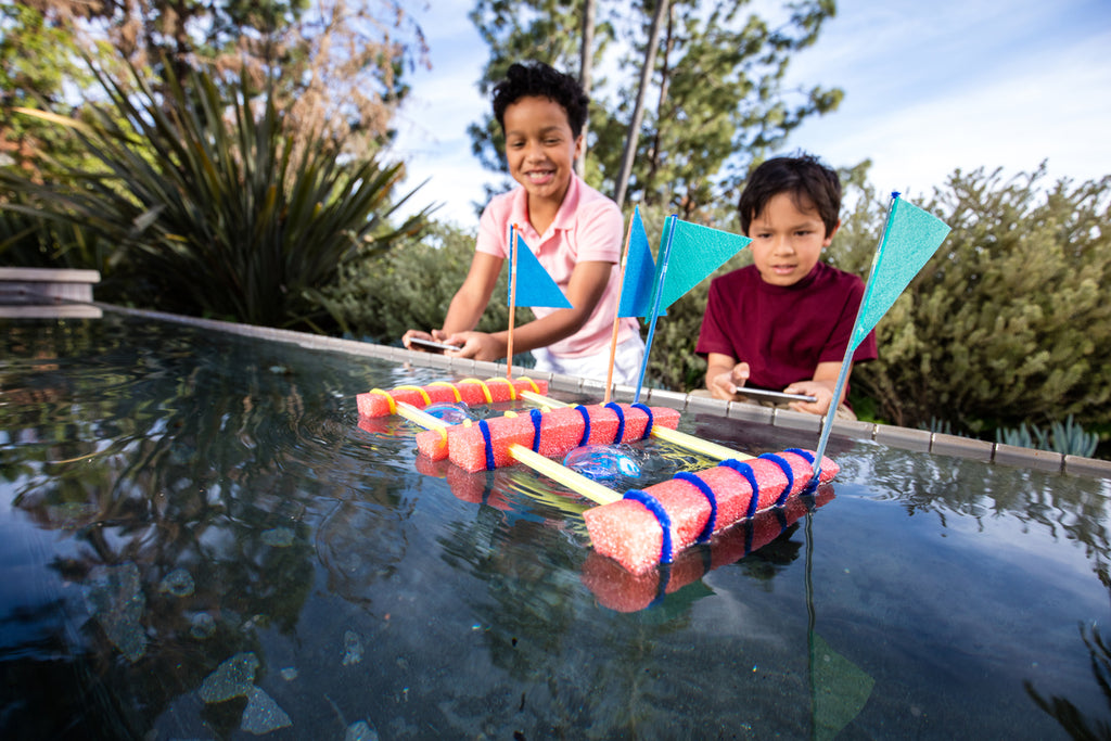 Two boys program their Sphero BOLTs in a pool.