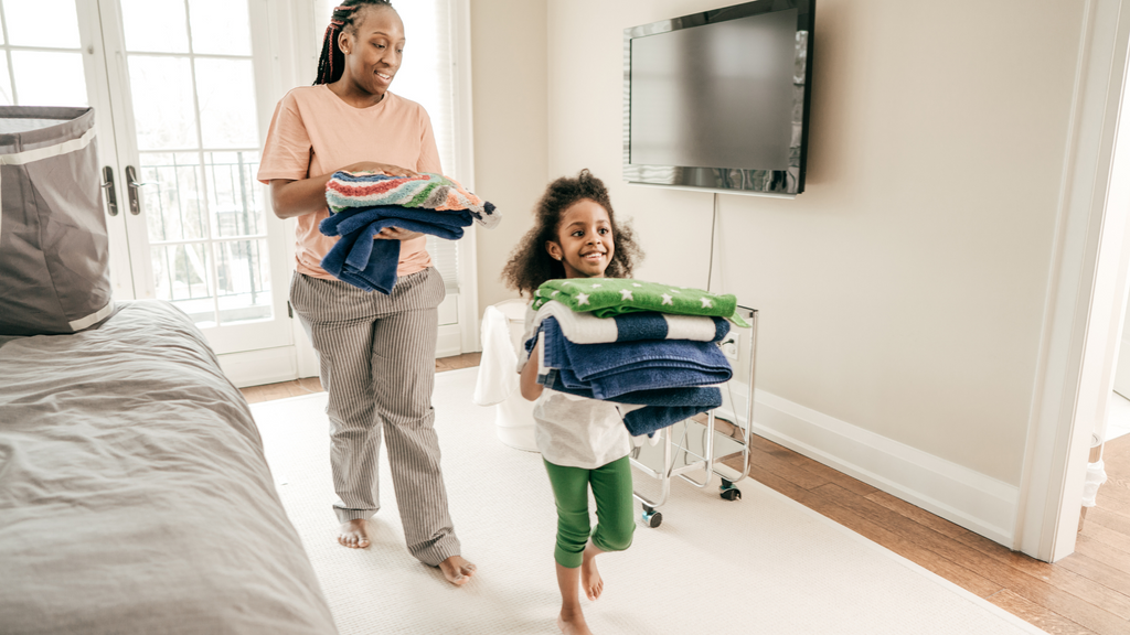 A young girl helps her mom put away laundry as part of her chores at home.