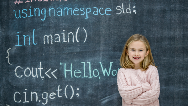 A girl stands in front of a chalkboard with code written on it.