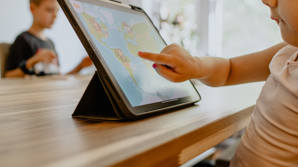 A young child explores on a tablet at a table.