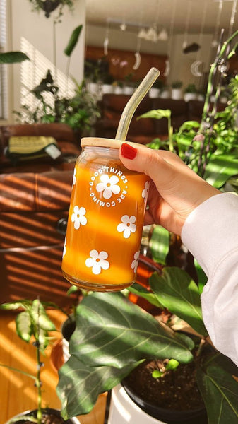 Meryum Designs Good Things Are Coming Glass Cup Held by someone's hand in front of a bunch of plants