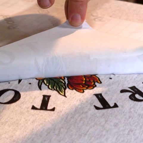 hand peeling off transfer paper off a print