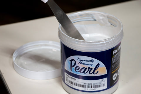 a quart container of pearl ink with a spatula in it
