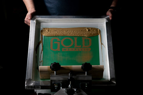 a person lifting up a screen on press. the screen says gold