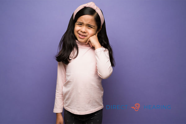 A child holding their ear in pain, a common symptom of ear infections which can be caused by contagious viruses or bacteria, such as the one related to the keyword are ear infections contagious