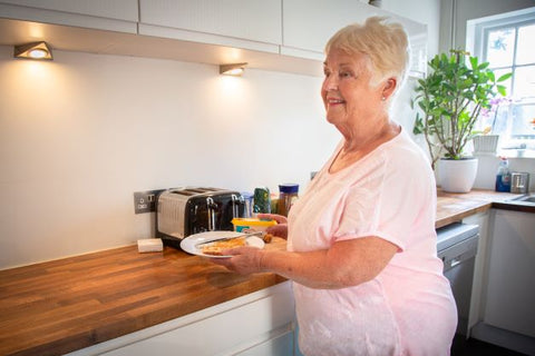 Old woman with smart home monitoring solutions setup in kitchen