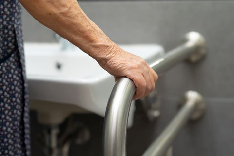 Elderly woman holding rails in the bathroom