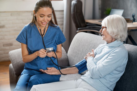 Female nurse taking blood pressure of elderly