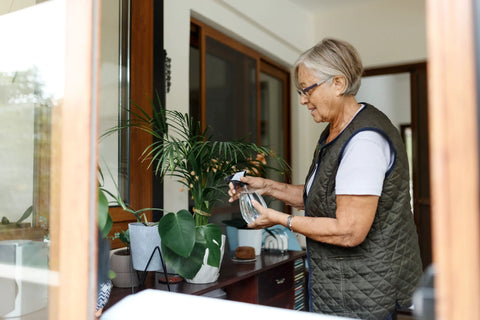 Elderly woman taking care of indoor potted plants