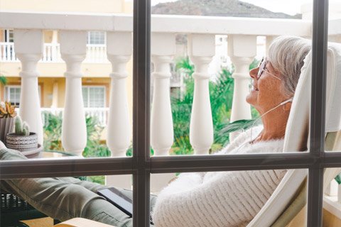 Elderly lady relaxing on apartment balcony