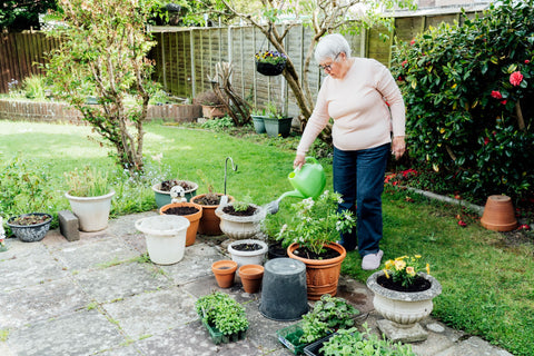 Elderly woman with dementia watering plants in her garden