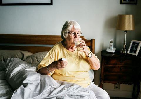 Elderly woman taking medicines before bed