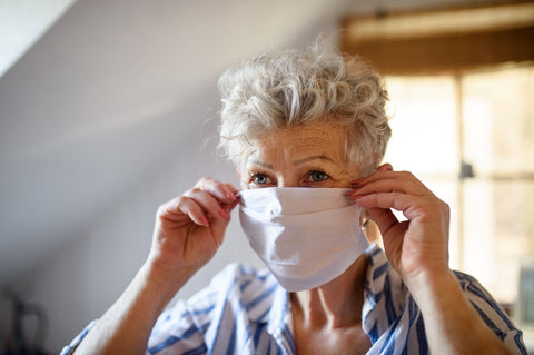 Elderly woman wearing mask while cleaning