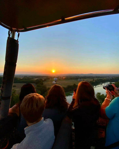 Passagers qui découvrent un lever de soleil lors d'un tour en montgolfière