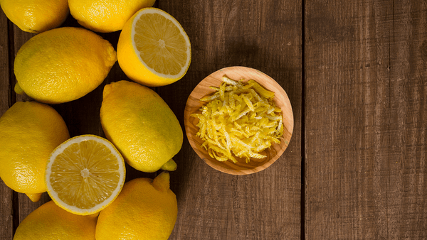 Lemons on table with lemon zest in small bowl